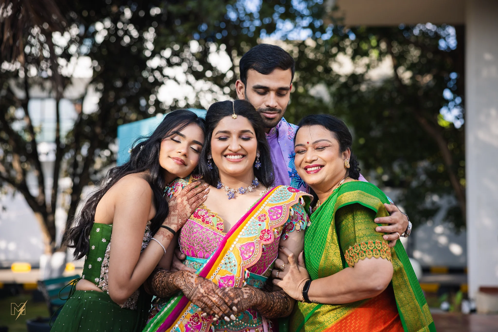 Indian bride posing with her parents in traditional wedding attire during a candid family moment.