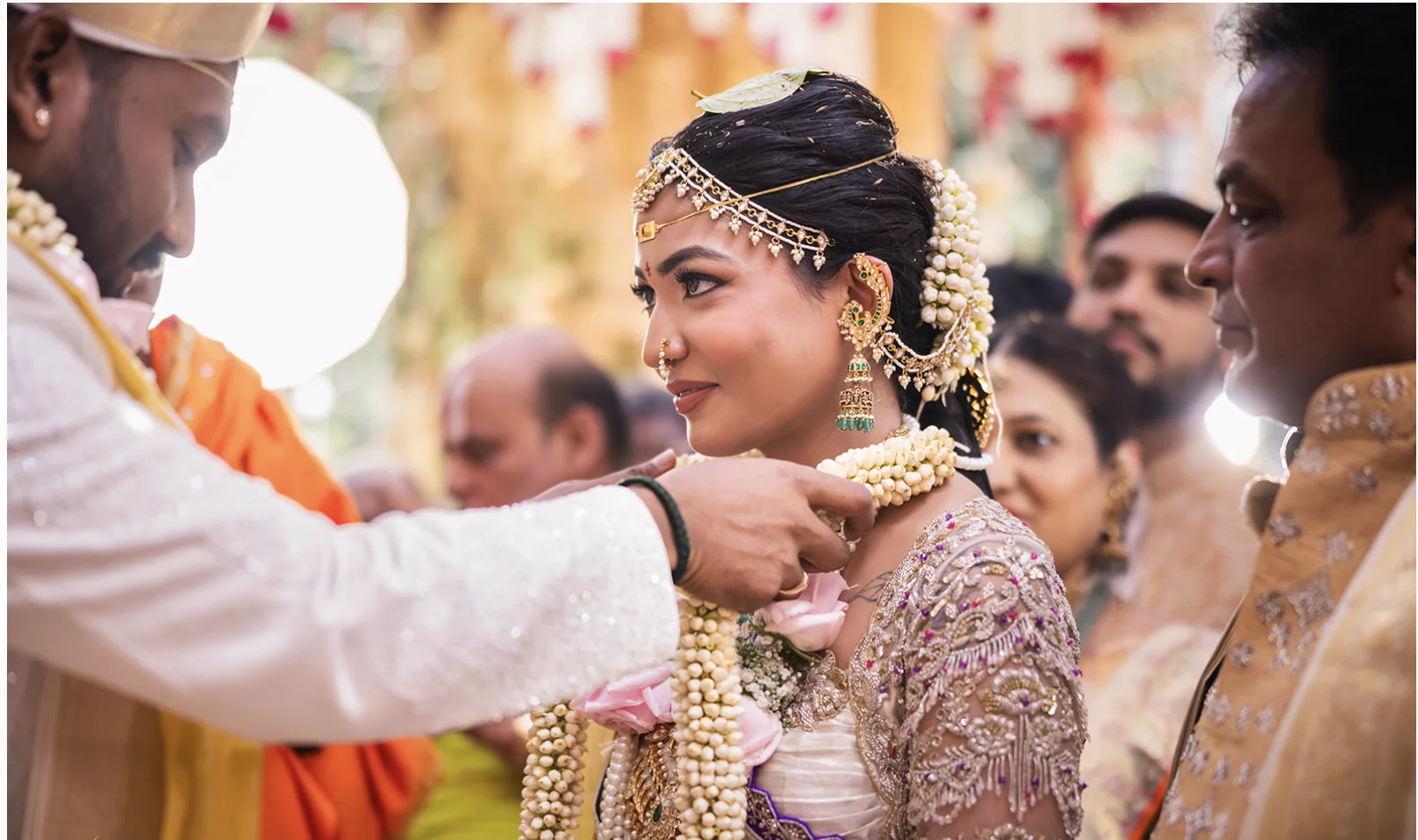 South Indian groom placing a jasmine garland on the smiling bride during their wedding ceremony.